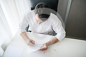 Handsome brunette businessman writing and working in the office with a paper and a pen in his hand.