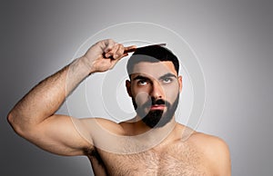 Handsome brunette middle eastern man brushing his hair