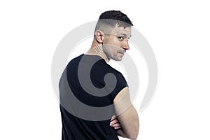 A handsome brutal man in a black T-shirt looks over his shoulder. Isolated on a white background
