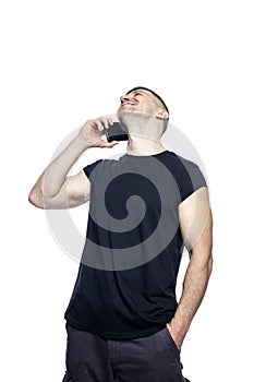 A handsome brutal man in a black t-shirt is talking on the phone and laughing. Business and technology. Isolated on white