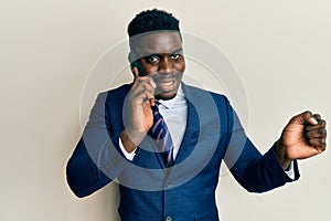 Handsome business black man having conversation talking on the smartphone screaming proud, celebrating victory and success very