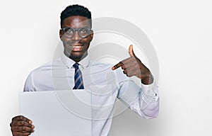 Handsome business black man holding blank empty banner pointing finger to one self smiling happy and proud