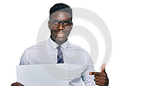 Handsome business black man holding blank empty banner smiling happy pointing with hand and finger