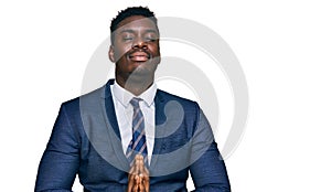 Handsome business black man wearing business suit and tie begging and praying with hands together with hope expression on face