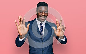 Handsome business black man wearing business suit and tie showing and pointing up with fingers number eight while smiling