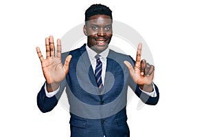 Handsome business black man wearing business suit and tie showing and pointing up with fingers number seven while smiling
