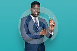 Handsome business black man wearing business suit and tie smiling with happy face winking at the camera doing victory sign