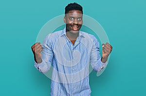 Handsome business black man wearing casual striped t shirt screaming proud, celebrating victory and success very excited with