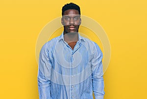 Handsome business black man wearing casual striped t shirt with serious expression on face