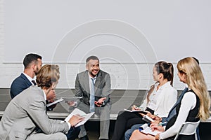 handsome business coach looking at businesspeople during training