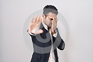 Handsome business hispanic man standing over white background covering eyes with hands and doing stop gesture with sad and fear