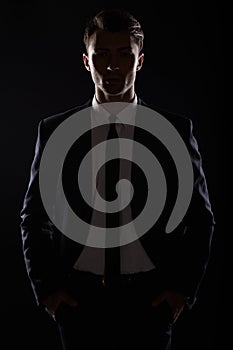 Handsome business man in black suite, backlight photo