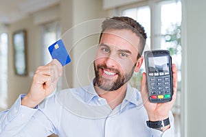 Handsome business man holding pos terminal and credit card, buying and payment using dataphone