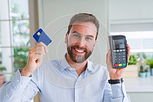 Handsome business man holding pos terminal and credit card, buying and payment using dataphone