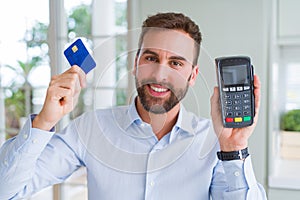 Handsome business man holding pos terminal and credit card, buying and payment using dataphone