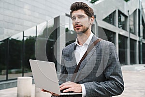 Handsome business man outdoors using laptop