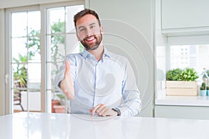 Handsome business man smiling friendly offering handshake as greeting and welcoming