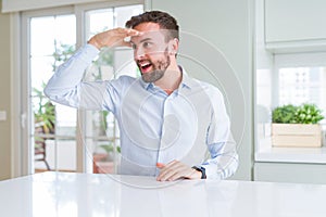 Handsome business man very happy and smiling looking far away with hand over head