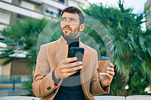 Handsome business man wearing elegant jacket using smartphone outdoors