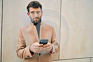 Handsome business man wearing elegant jacket using smartphone outdoors