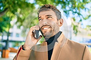 Handsome business man wearing elegant jacket using smartphone smiling happy outdoors