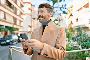 Handsome business man wearing elegant jacket using smartphone smiling happy outdoors