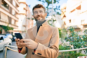 Handsome business man wearing elegant jacket using smartphone smiling happy outdoors