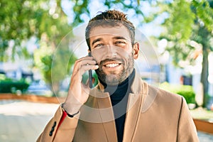 Handsome business man wearing elegant jacket using smartphone smiling happy outdoors