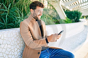 Handsome business man wearing elegant jacket using smartphone smiling happy outdoors