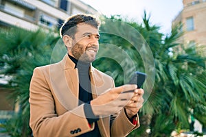 Handsome business man wearing elegant jacket using smartphone smiling happy outdoors