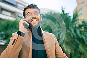 Handsome business man wearing elegant jacket using smartphone smiling happy outdoors