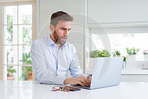 Handsome business man working using computer laptop scared in shock with a surprise face, afraid and excited with fear expression