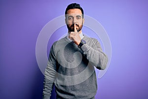 Handsome businessman with beard wearing casual tie standing over purple background asking to be quiet with finger on lips