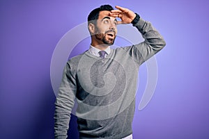 Handsome businessman with beard wearing casual tie standing over purple background very happy and smiling looking far away with