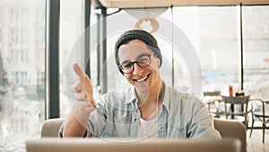 Handsome businessman in casual wear and eyeglasses is using a laptop in cafe