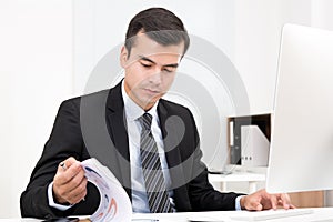 Handsome businessman concentrated on reading documents at his desk