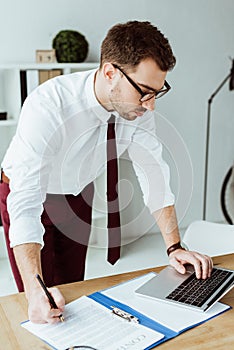 handsome businessman doing paperwork and working with laptop