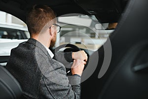 Handsome businessman driving car to airport, going on business side view, copy space. Happy man in stylish suit going to