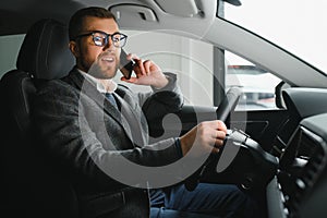 Handsome businessman driving car to airport, going on business side view, copy space. Happy man in stylish suit going to