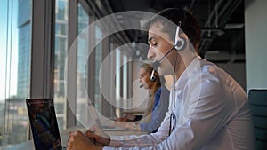 Handsome businessman entrepreneur in headset calling to cuctomers in business office call center