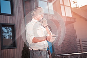 Handsome businessman feeling cheerful while calling his wife on way to work