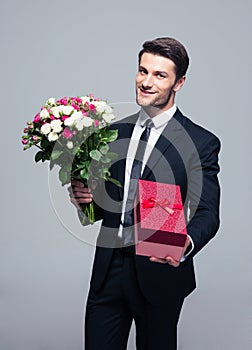 Handsome businessman with flowers and gift box