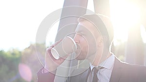 Handsome businessman in formal wear holding a cup of coffee while looking to the side.