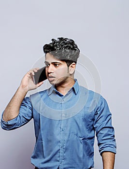 Handsome businessman in formals anxious on phone while talking to client in grey background