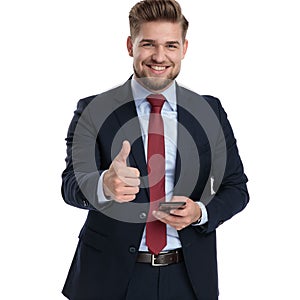 Handsome businessman gesturing ok and holding his phone