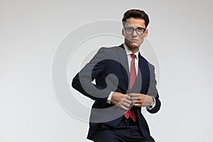 Handsome businessman with glasses unbuttoning navy blue suit