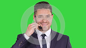 Handsome businessman with headset looking into camera and smiling on a Green Screen, Chroma Key.