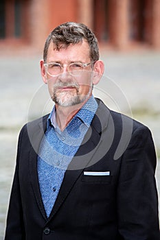 Handsome businessman in his 50s with eyeglasses standing outside