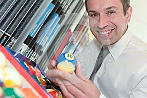 Handsome businessman holding billiard ball