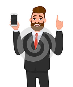 Handsome businessman holding/showing brand new smartphone/mobile/cell phone in hand and pointing index finger upside.